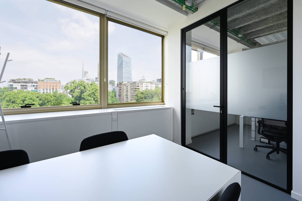 FERVI parete divisoria 6030 sala riunione parete vetrata a vetro doppio extra clear con effetto localizzato di privacy visiva e serigrafia personalizzata profilo in alluminio pure black ral 9005 porta a battente