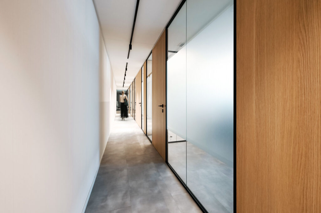 EPICA parete divisoria SLIM corridoio pareti vetrate a vetro singolo extra clear con profilo in alluminio jet black ral 9005 e pannello cieco colore oak