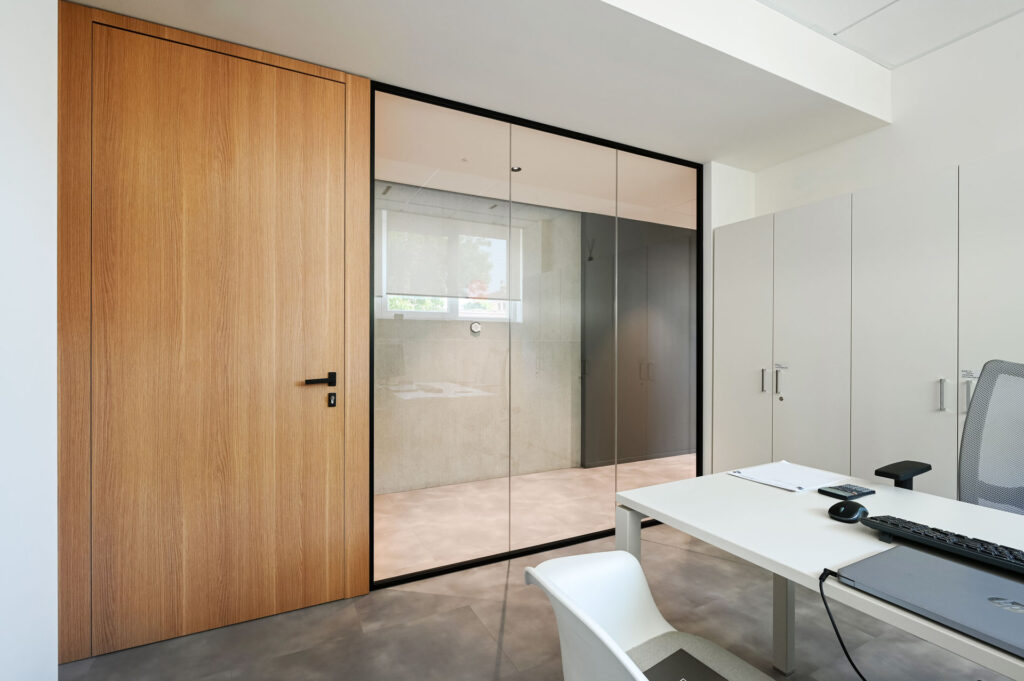 EPICA parete divisoria SLIM ufficio privato pareti vetrate a vetro singolo extra clear con profilo in alluminio jet black ral 9005 e porte a battente con anta cieca in legno colore oak