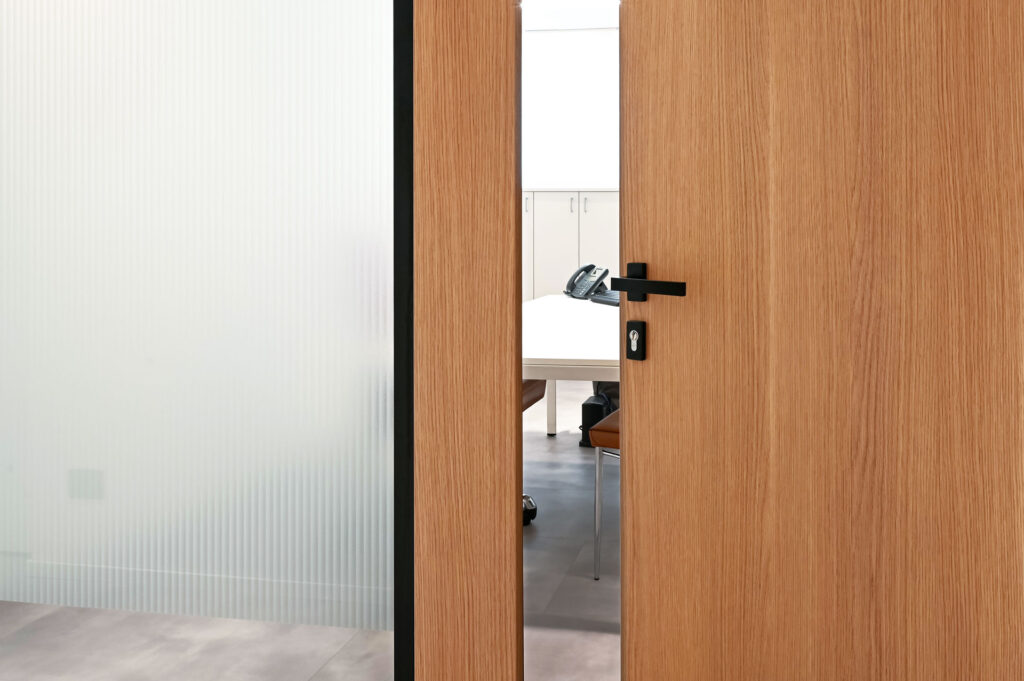 EPICA parete divisoria SLIM pareti vetrate a vetro singolo extra clear con profilo in alluminio jet black ral 9005 e porte a battente con anta cieca in legno colore oak dettaglio porta