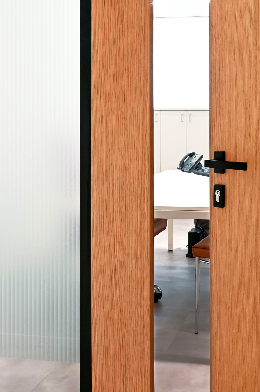 EPICA parete divisoria SLIM pareti vetrate a vetro singolo extra clear con profilo in alluminio jet black ral 9005 e porte a battente con anta cieca in legno colore oak dettaglio porta