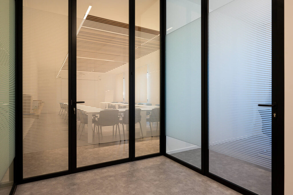 FERRUNION parete divisoria Glass corridoio parete vetrata a vetro singolo extra clear con serigrafia personalizzata per privacy visiva profilo in alluminio black ral 9005 porta a battente dettaglio effetto visual privacy