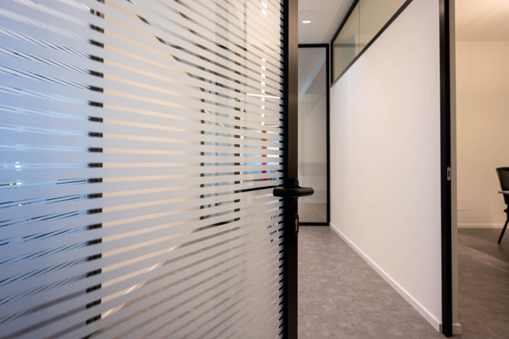 FERRUNION parete divisoria Glass corridoio parete vetrata a vetro singolo extra clear con serigrafia personalizzata per privacy visiva profilo in alluminio black ral 9005 porta a battente dettaglio effetto visual privacy