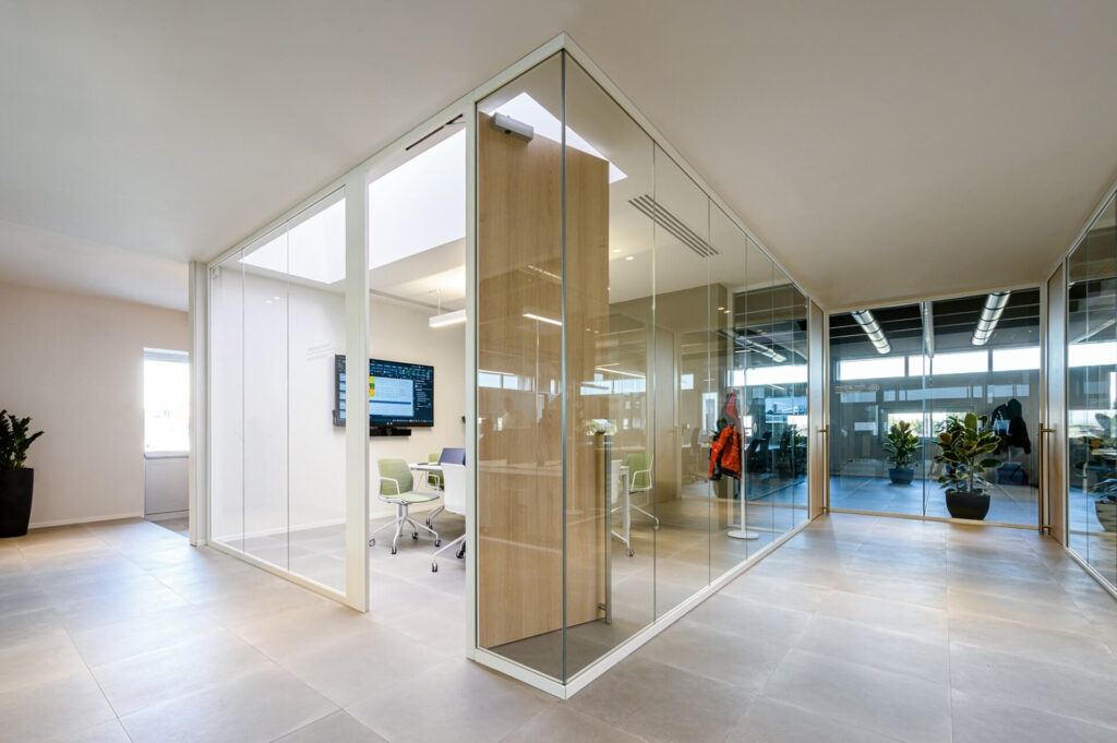 FRIUL INTAGLI INDUSTRIE corridoio sala riunione parete divisoria Glass parete vetrata a vetro singolo extra clear profilo in alluminio pure white rat 9010 e porte a battente con anta cieca in legno colore oak dettaglio angolo giunzione parete