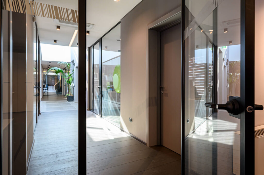 SKEMA parete divisoria Slim corridoio parete vetrata a vetro singolo extra clear profilo in alluminio jet black ral 9005 e porte a battente dettaglio porta aperta